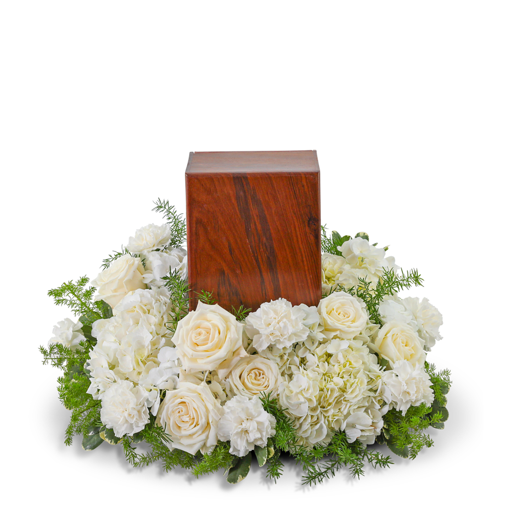 White roses and carnations surround a wooden urn.