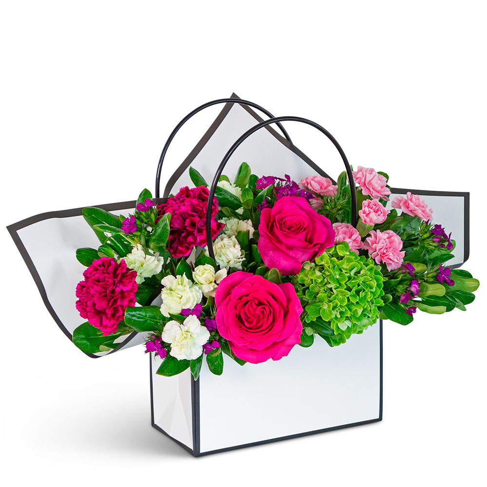Pink and white floral arrangement in a white handled gift bag