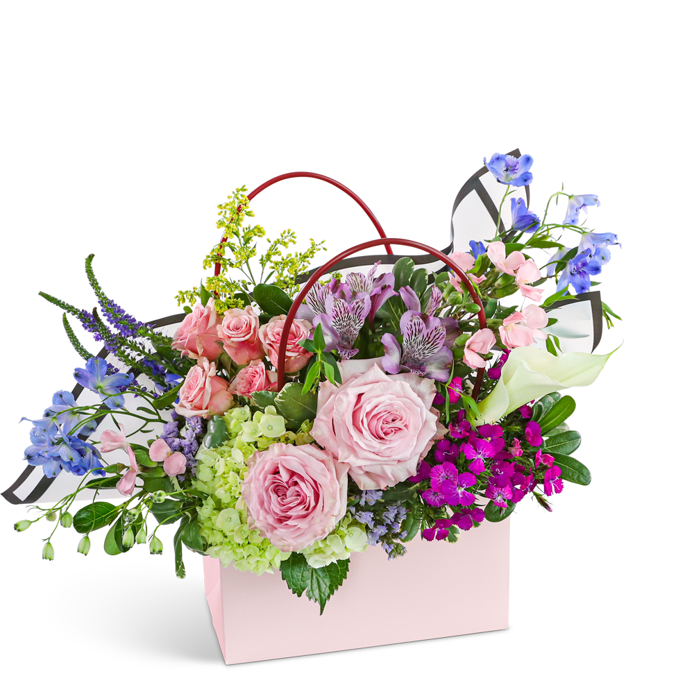 Mixed flower arrangement in a pink gift bag with red handles