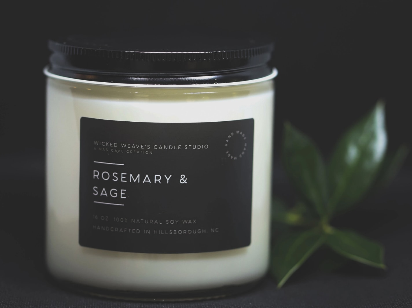Jar candle labeled rosemary and sage with a black lid