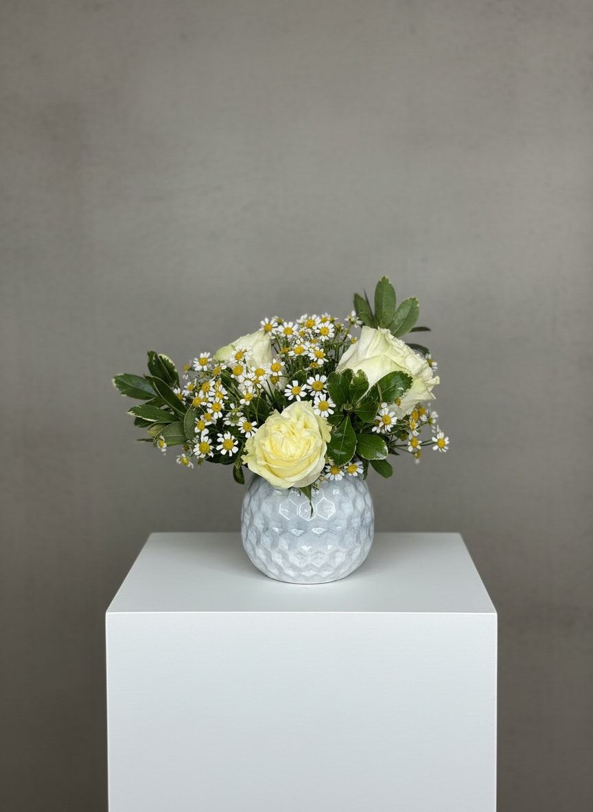 Yellow roses and white daisies in a textured white vase