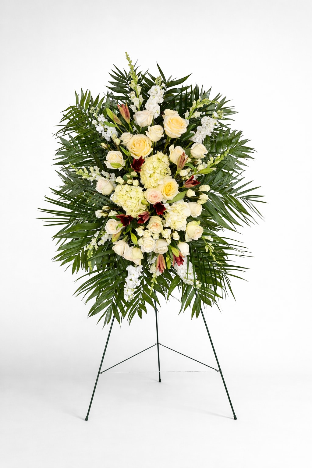 Tall standing spray of ivory roses and hydrangeas with palm fronds on a metal easel