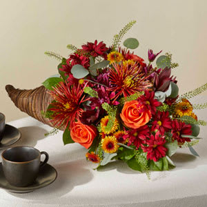 Celebrate Autumn Cornucopia - Celebrate everything you're thankful for with this iconic symbol of bounty and blessings resplendent with orange roses, bronze button pompons, red Leucadendron, and more.