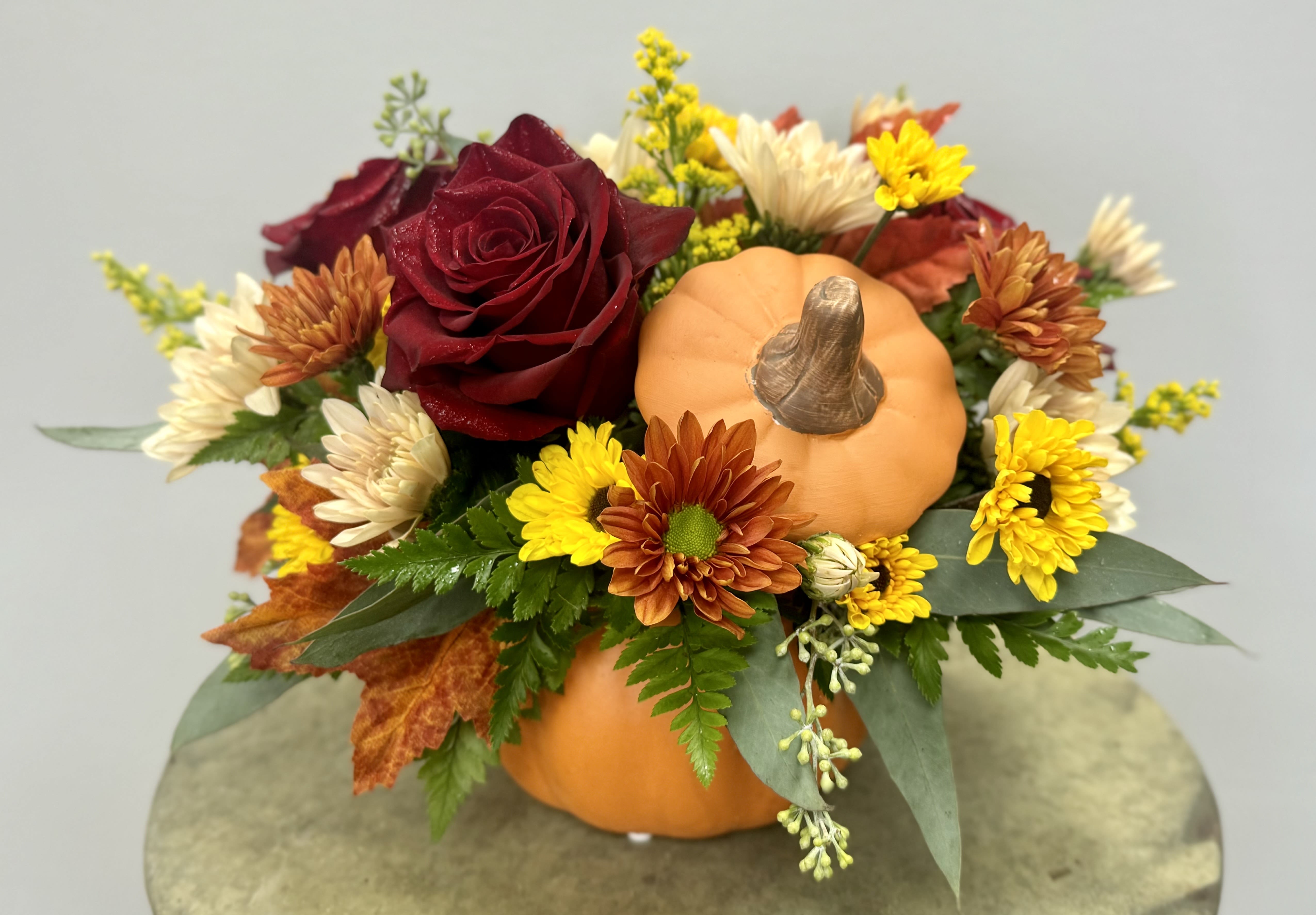 Fall floral arrangement with a pumpkin and red rose