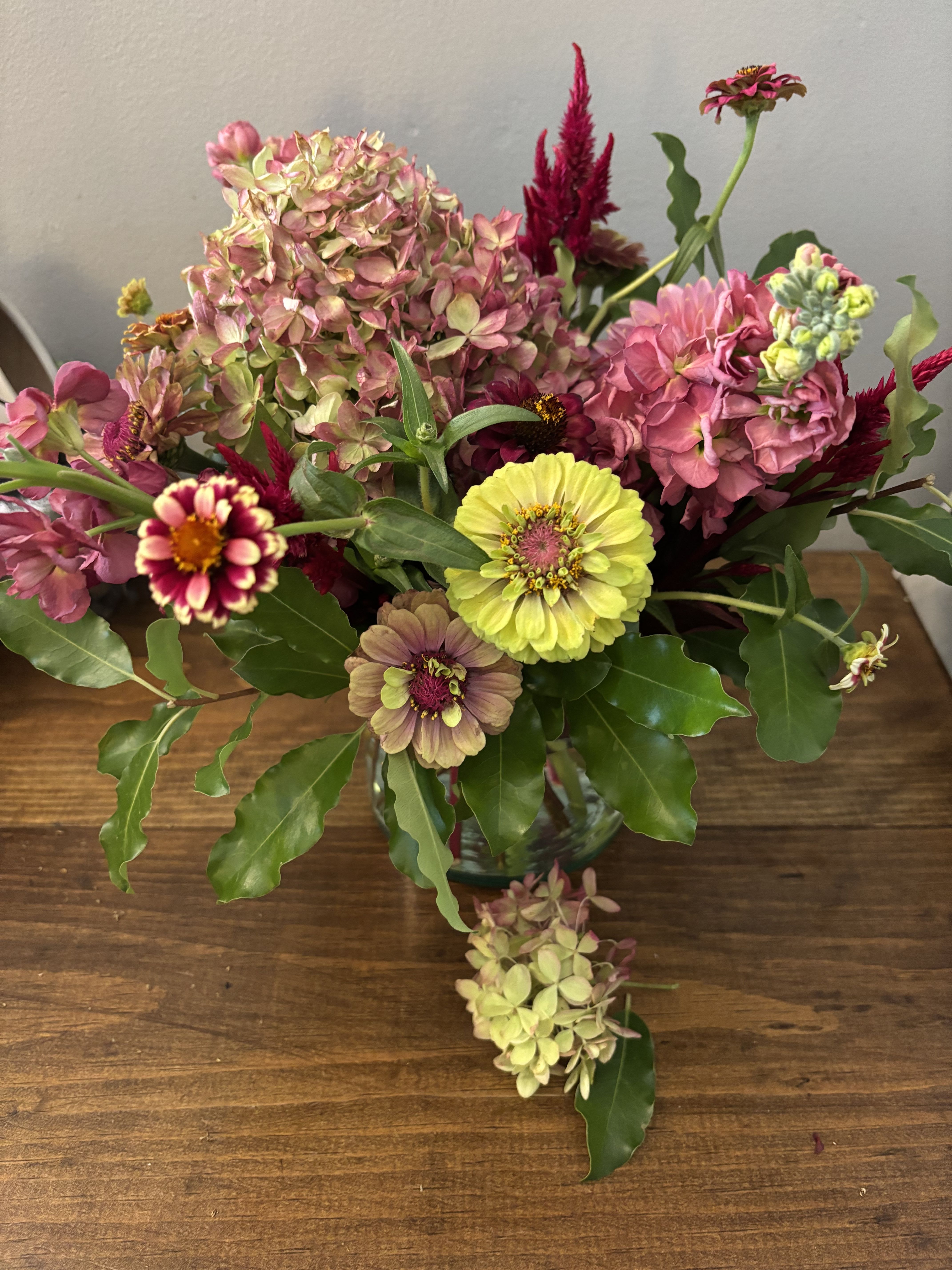 Mixed bouquet with pink hydrangeas, zinnias, and yellow blooms in a glass vase