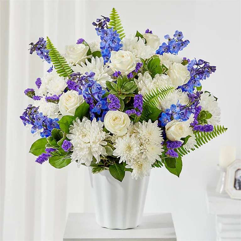 White and blue floral arrangement in a white vase