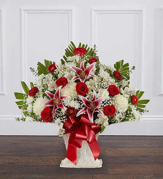 Large red and white floral arrangement with lilies and roses in a white container