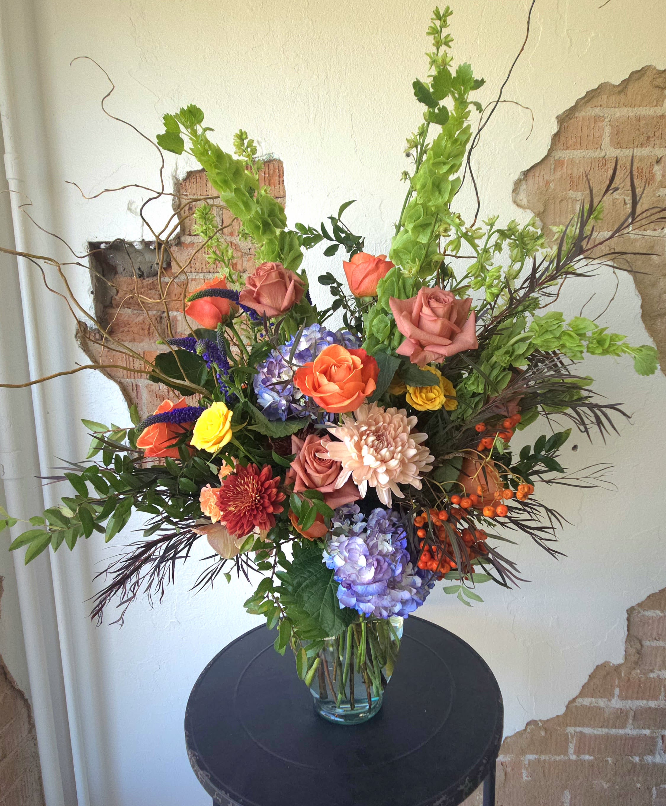 Mixed bouquet of roses, hydrangeas, and chrysanthemums in a glass vase