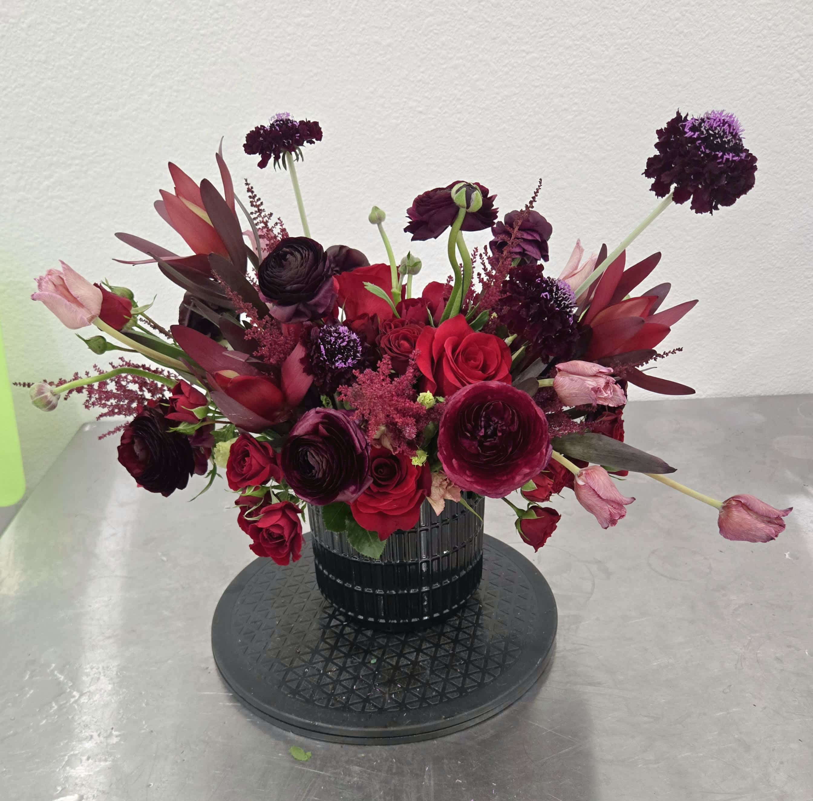 Deep red and burgundy bouquet in a black vase