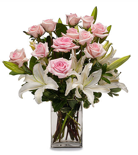 Pink roses and white lilies arranged in a clear glass vase