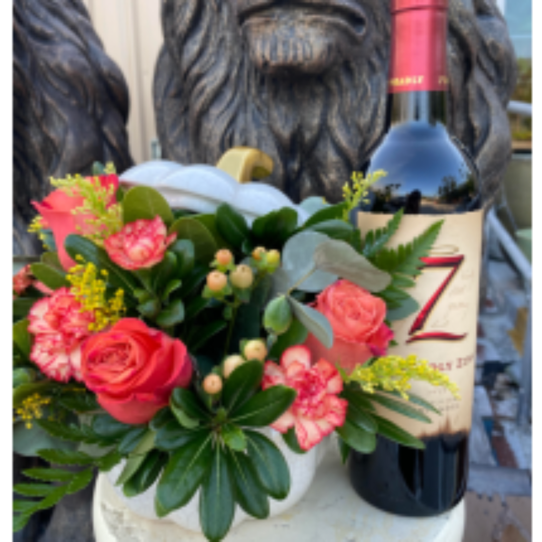 Pink rose and carnation arrangement beside a wine bottle