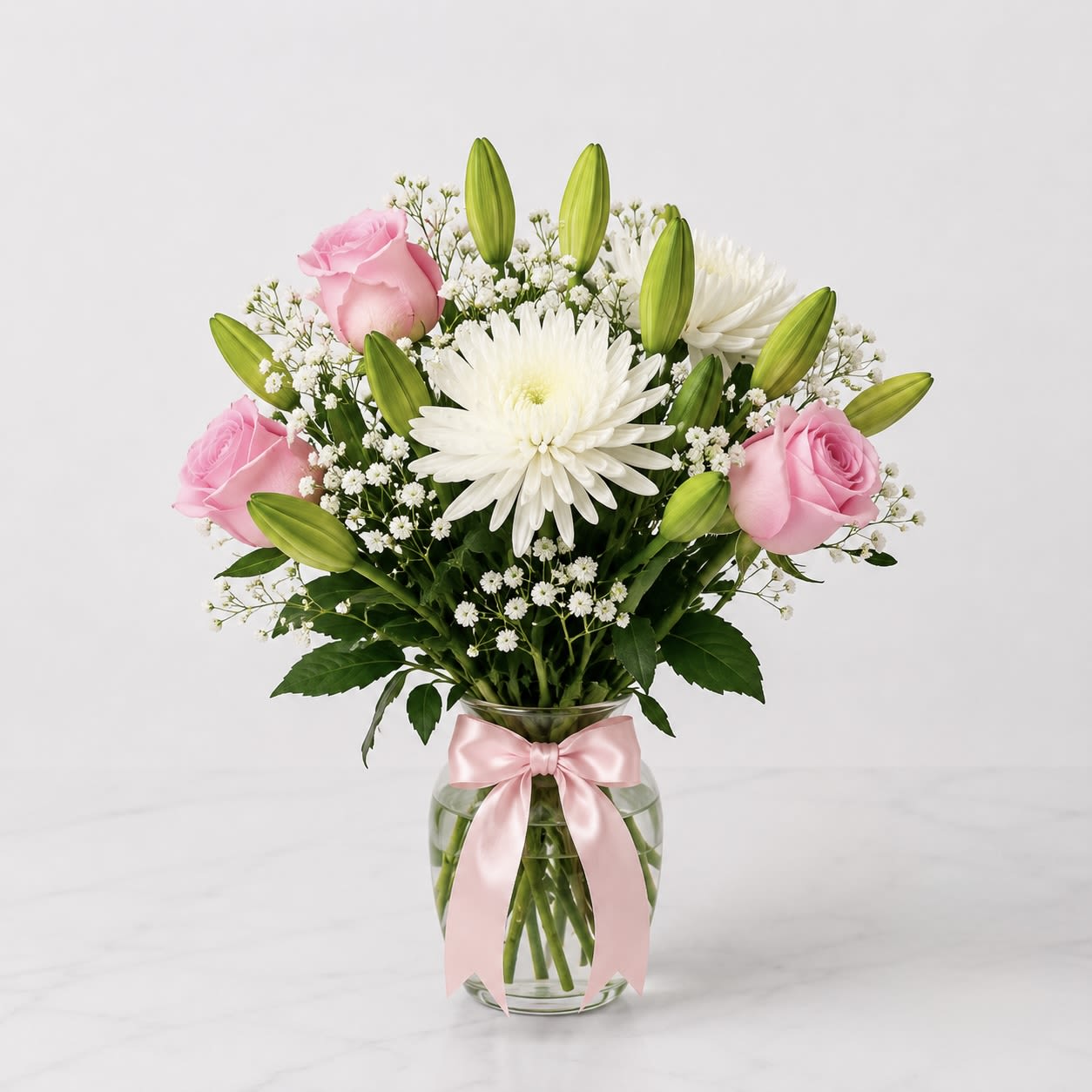 Blush Grace - A soft and elegant vase arrangement featuring delicate pink roses, fresh white blooms, and lush seasonal accents. Designed in a timeless garden style, this arrangement brings beauty, charm, and sophistication to any space.  Perfect for birthdays, get well wishes, thank you gifts, new baby celebrations, or simply brightening someone’s day. Handcrafted with fresh flowers and arranged in a glass vase for a beautiful presentation that is ready to enjoy upon arrival.  Flowers may vary slightly based on seasonal availability while maintaining the overall color palette, style, and value of the arrangement.