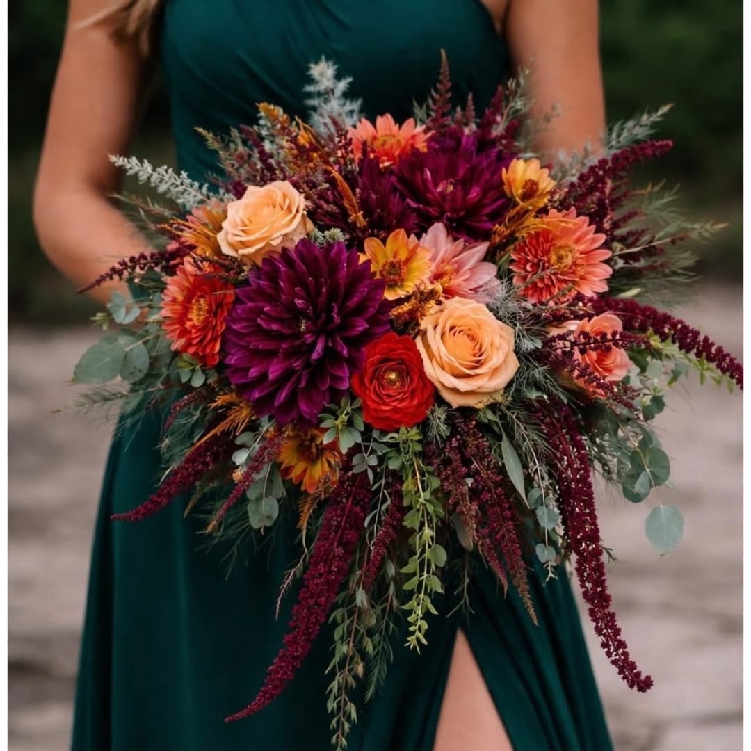 Woman holding a large bouquet of roses and dahlias in burgundy and peach tones