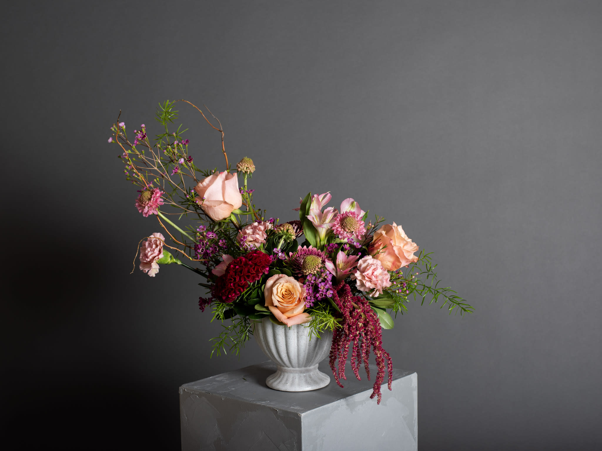 Mixed pink and peach flower arrangement in a white vase
