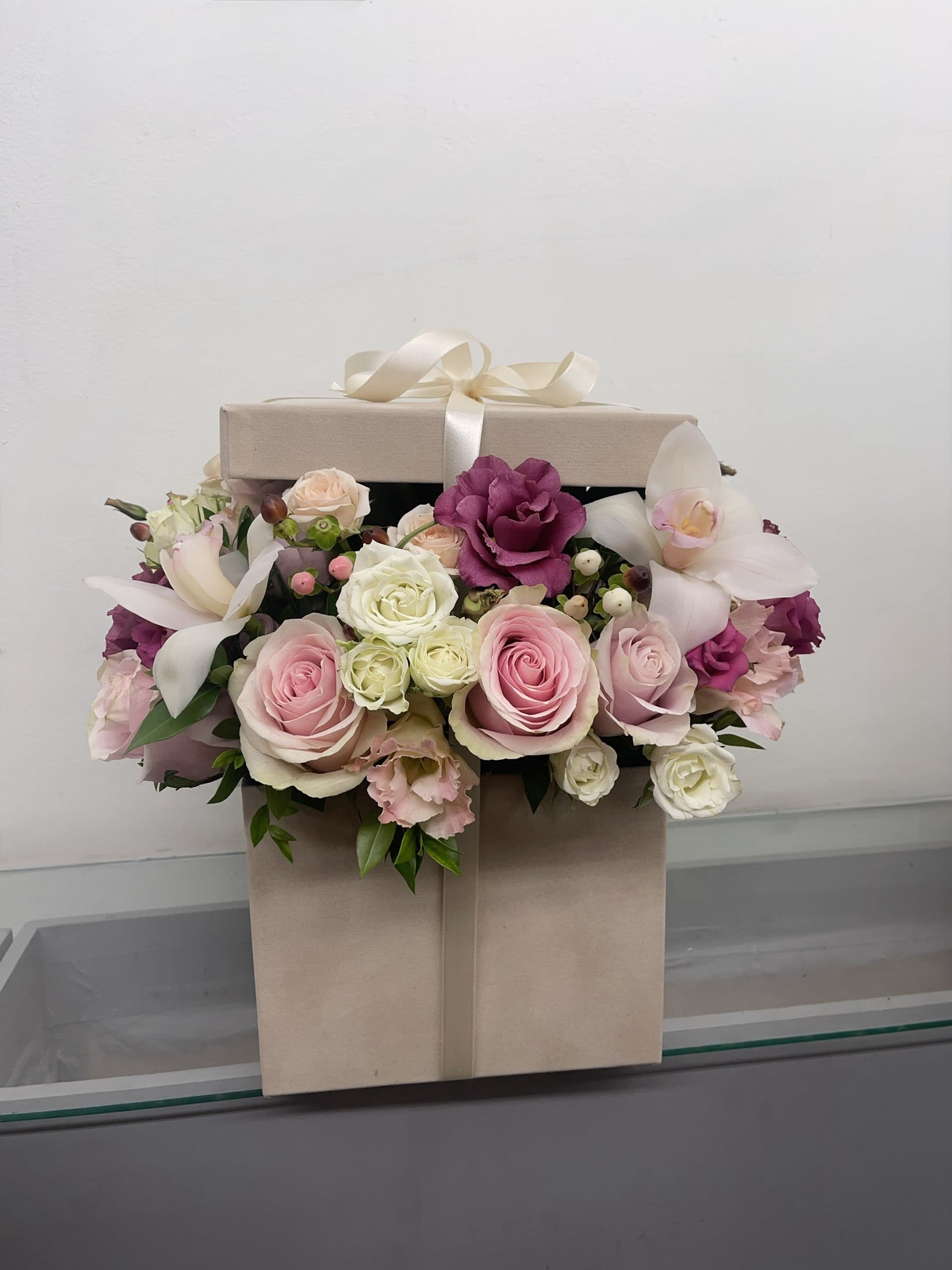 Pink and white roses with orchids in a beige gift box