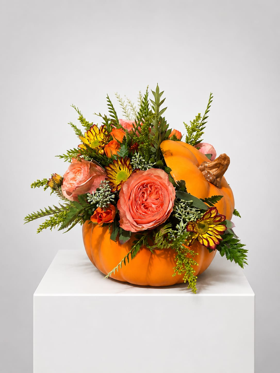 Orange pumpkin filled with pink and yellow flowers