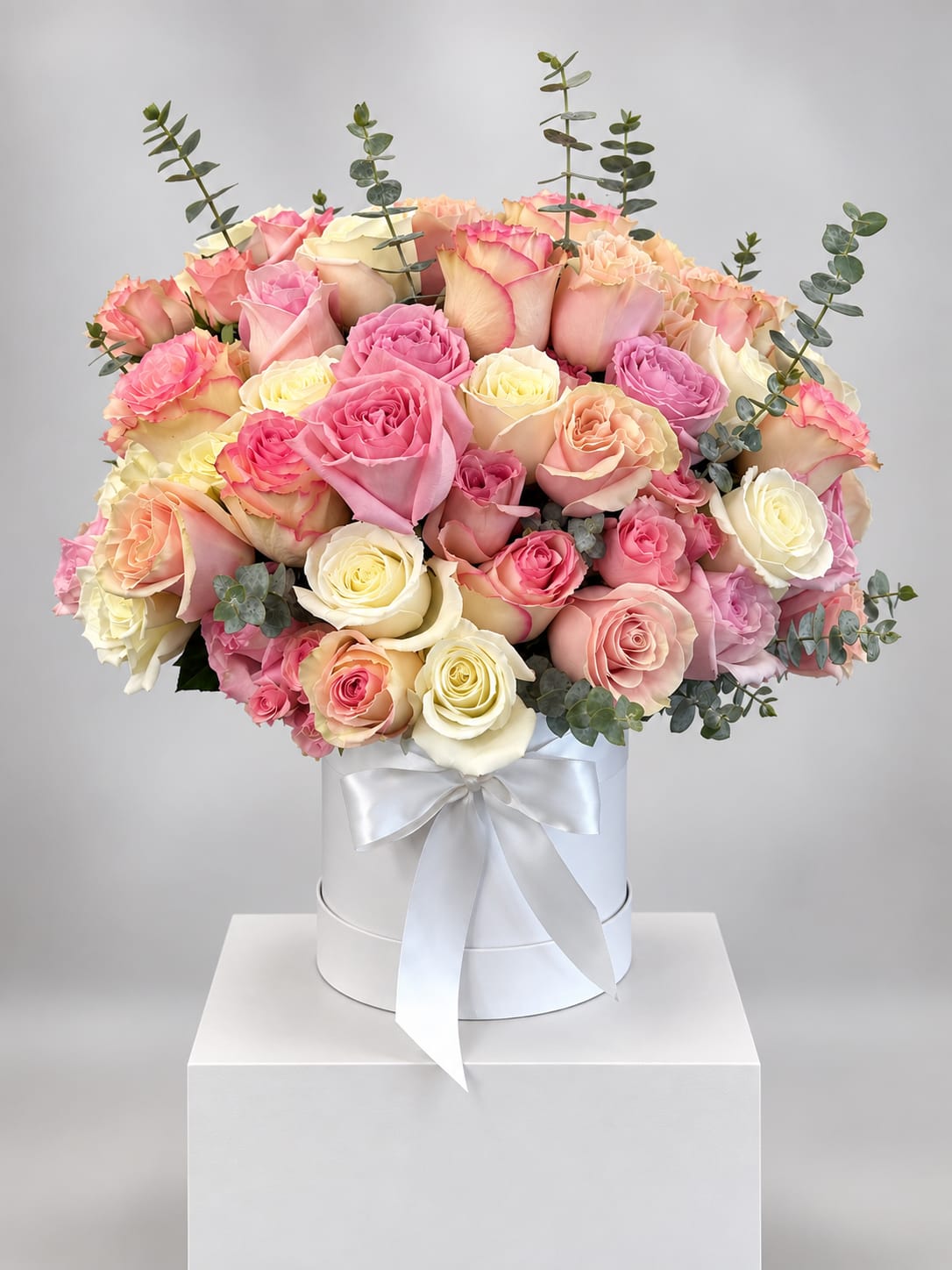 Bouquet of pink, peach, and cream roses in a white hat box with ribbon