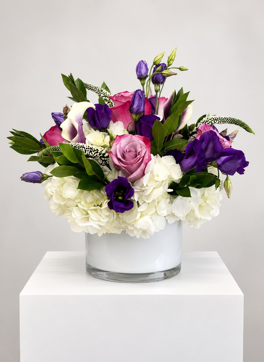 Pink and purple mixed flowers arranged in a clear glass vase