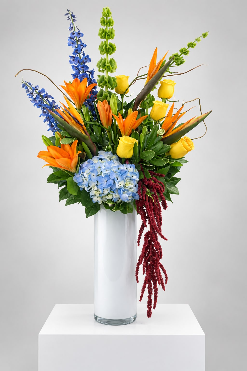 Colorful tropical bouquet in a tall white vase