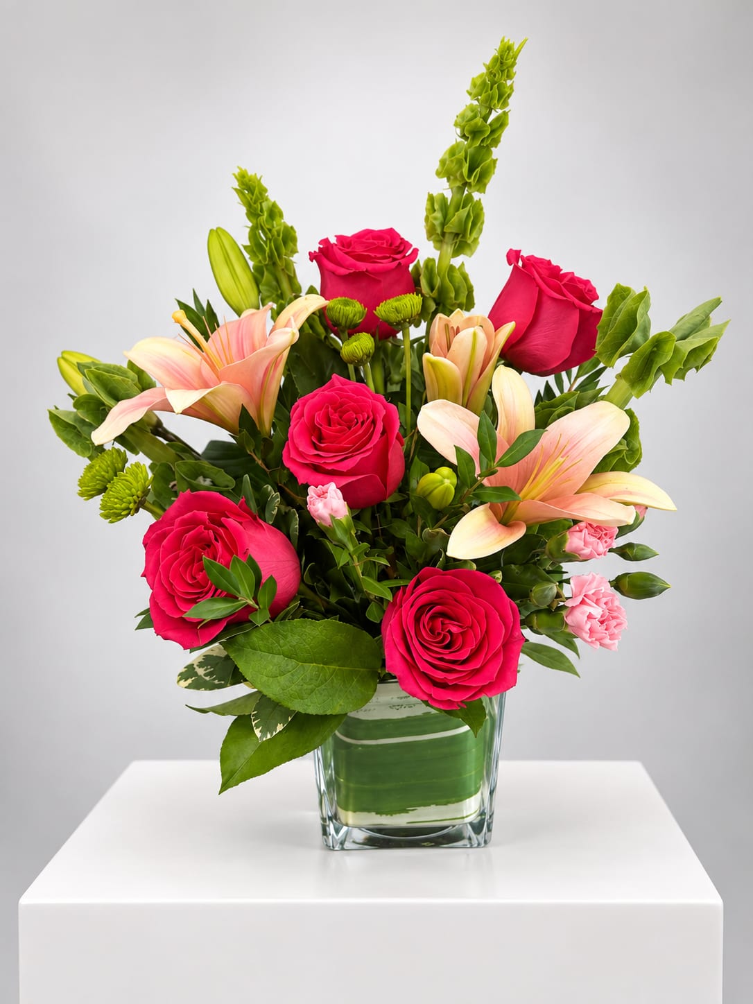 Pink roses and lilies arranged in a clear glass vase