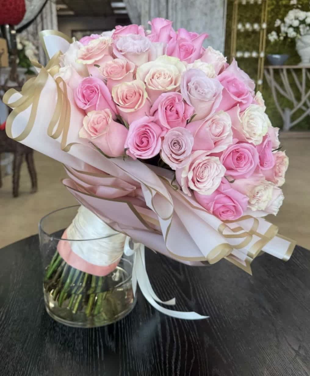 Bouquet of pink and white roses wrapped in pastel paper with ribbon