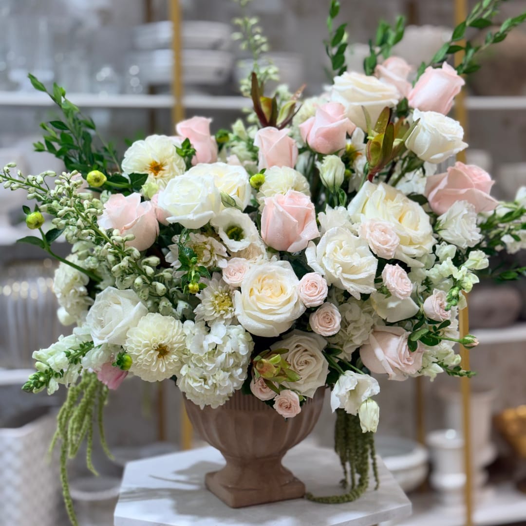 Large pastel rose arrangement in a brown urn vase