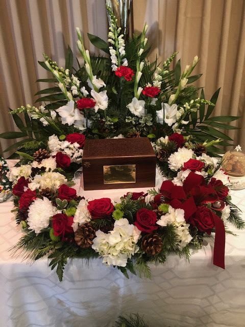Funeral wreath with red and white flowers around a wooden urn