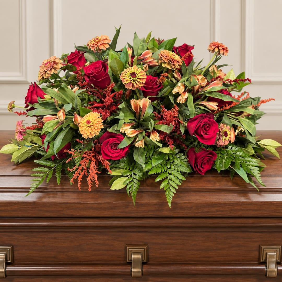 Red roses and orange flowers arranged on a casket