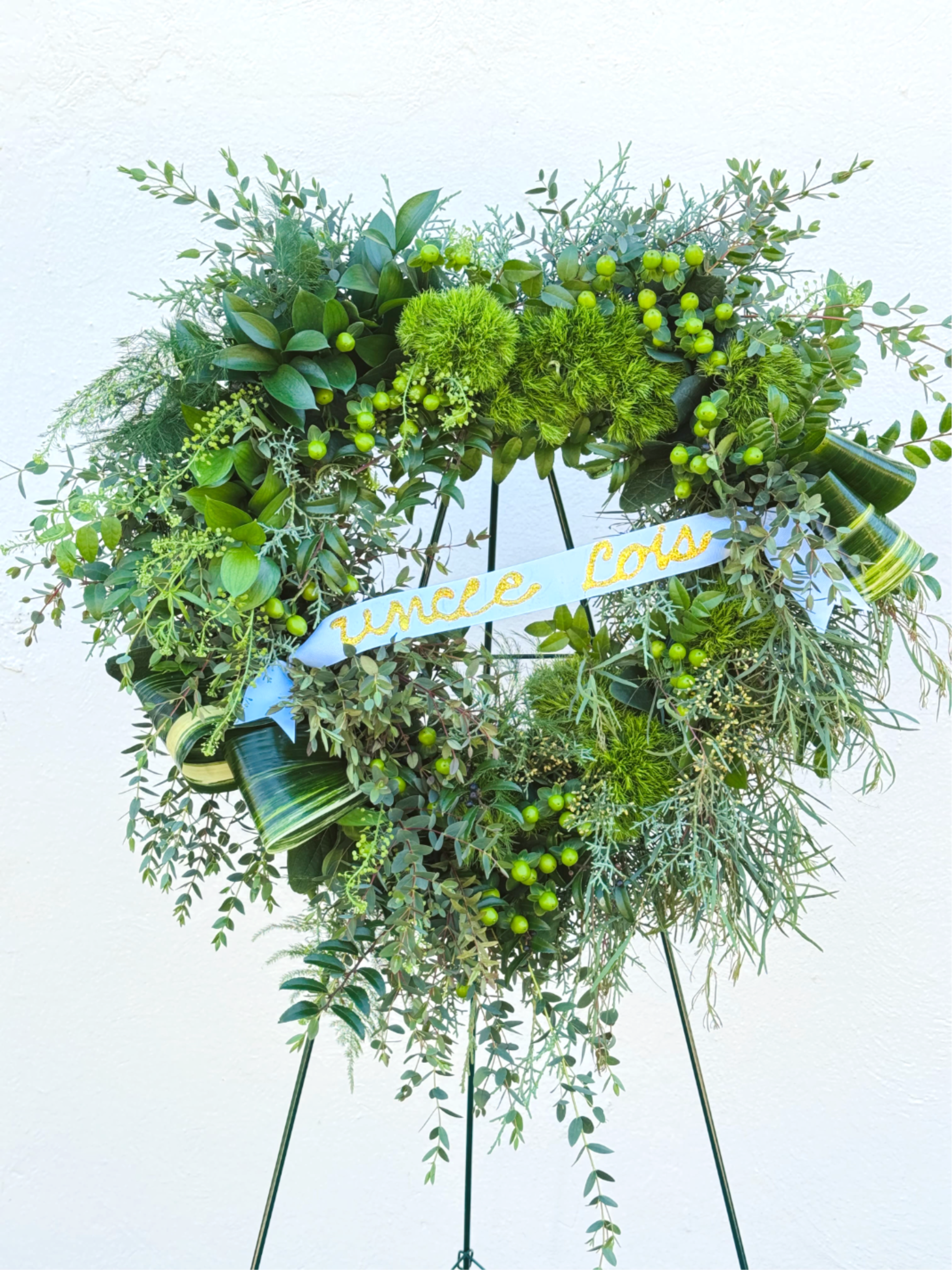 Heart-shaped green wreath on an easel with a blue ribbon