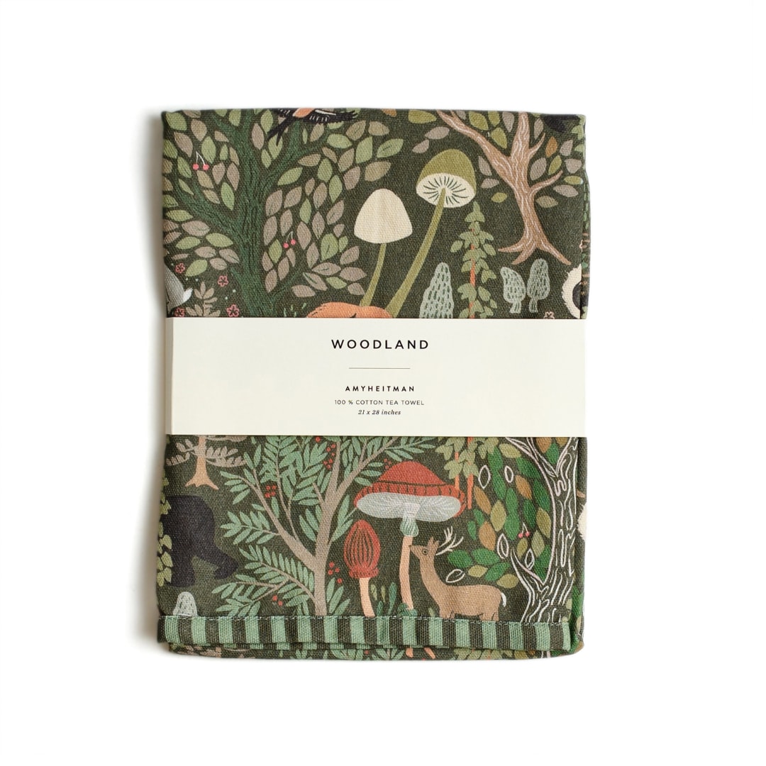 Folded woodland-print tea towel with mushrooms and trees
