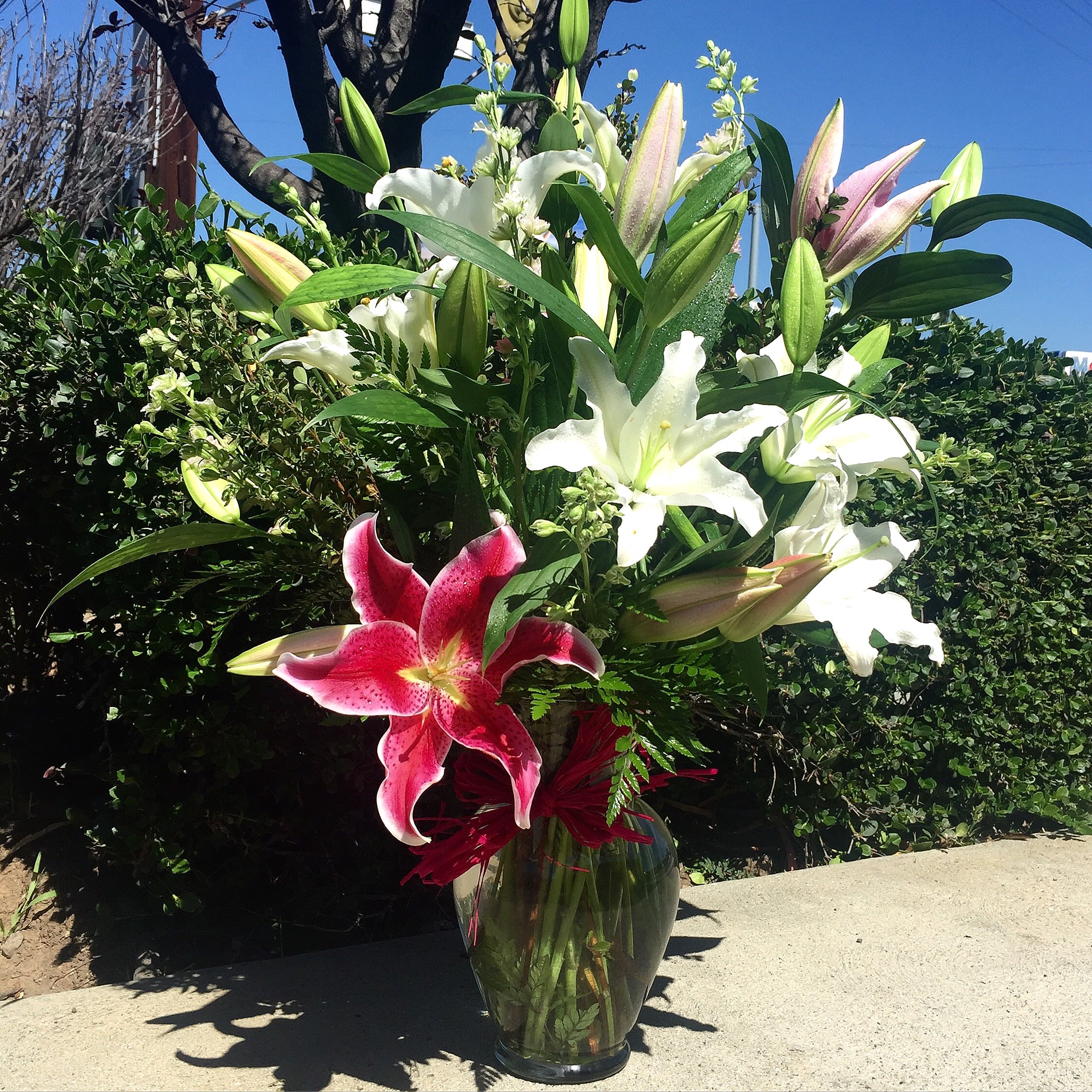 Tall bouquet of lilies in a clear glass vase with pink, white, and green blooms