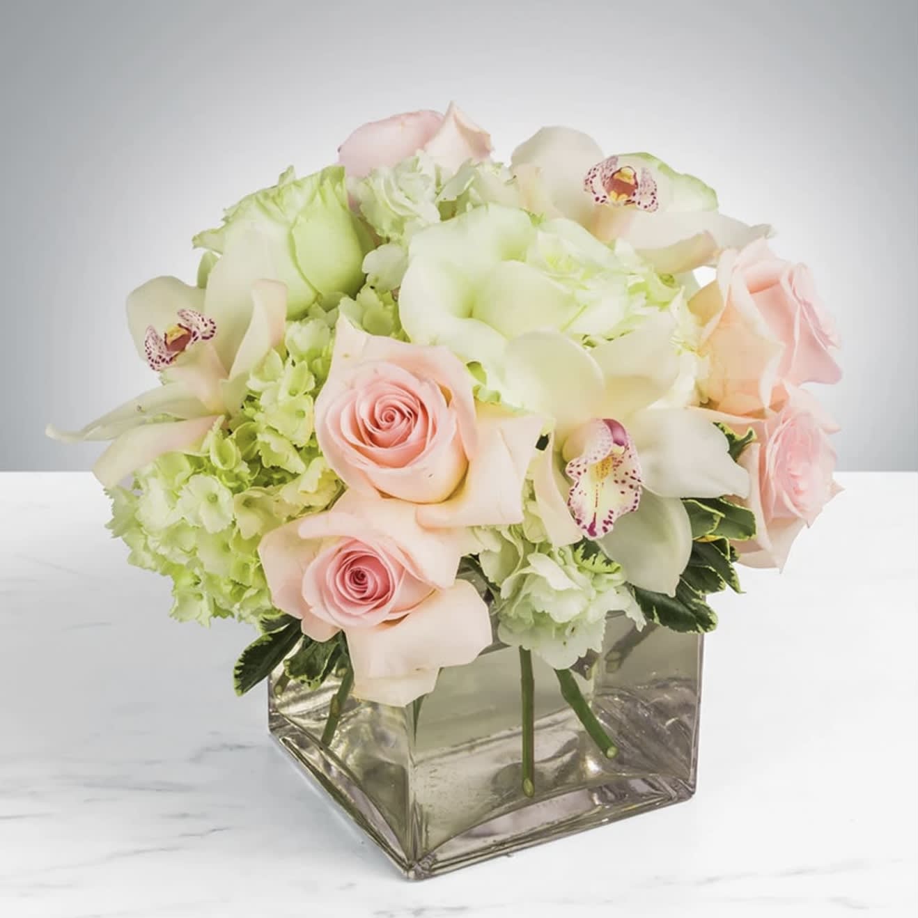 Elegant Bouquet - This elegant bouquet of cymbidium orchids, roses and hydrangeas arranged in a keepsake glass cube vase is the epiphany that there is beauty in simplicity! The perfect gift for all occasion suited for home or office.  Approximately 10" D