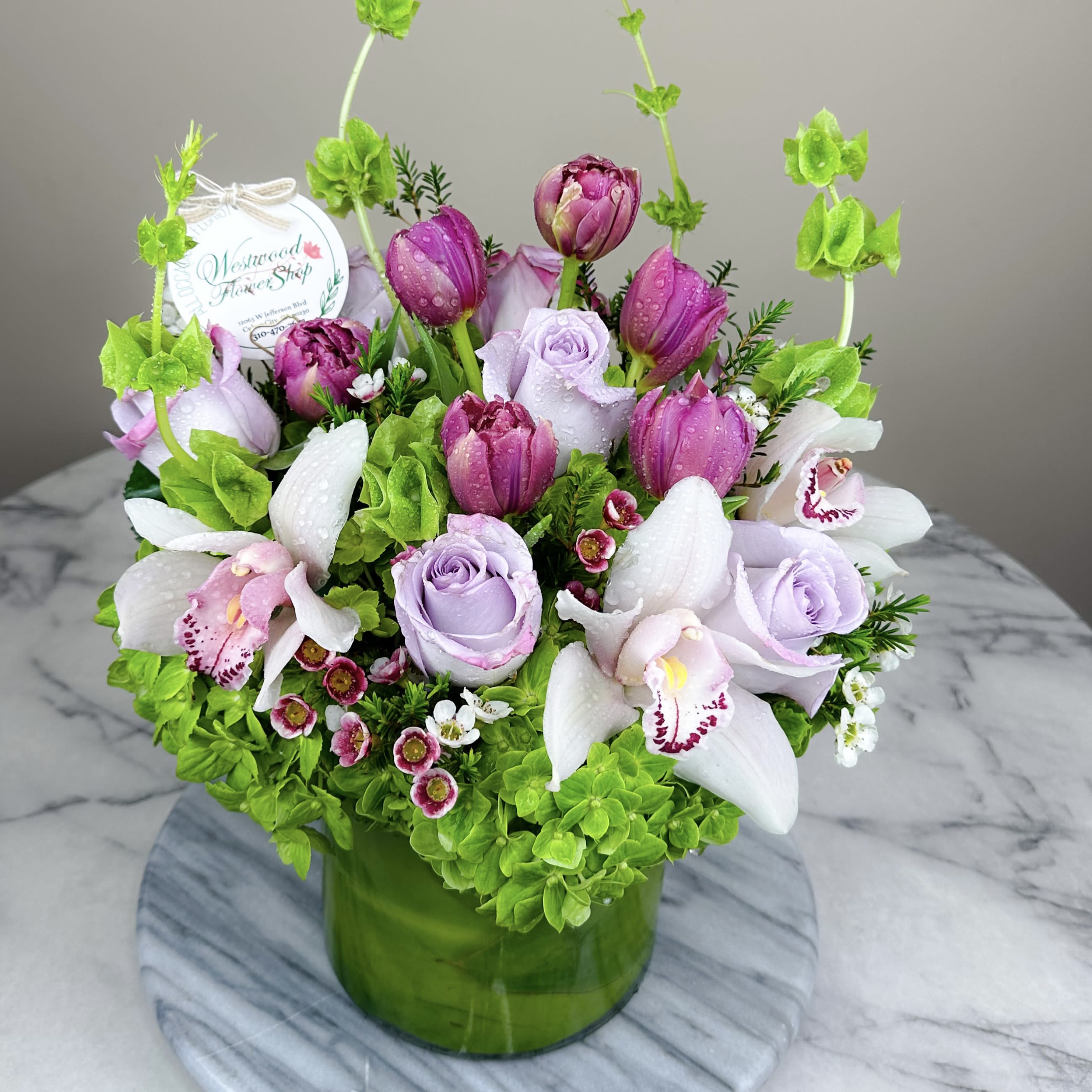Pink and lavender flowers arranged in a green glass vase
