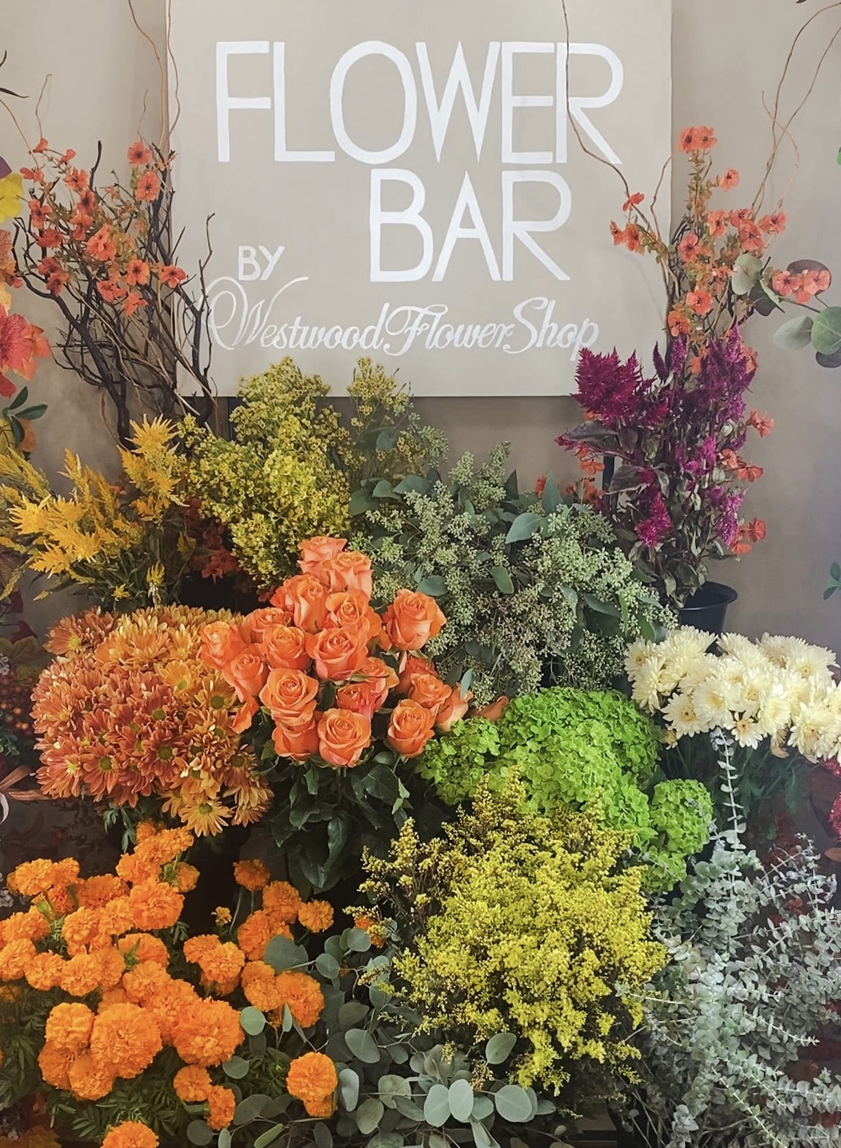 Assorted flower display with roses, chrysanthemums, and tall branches