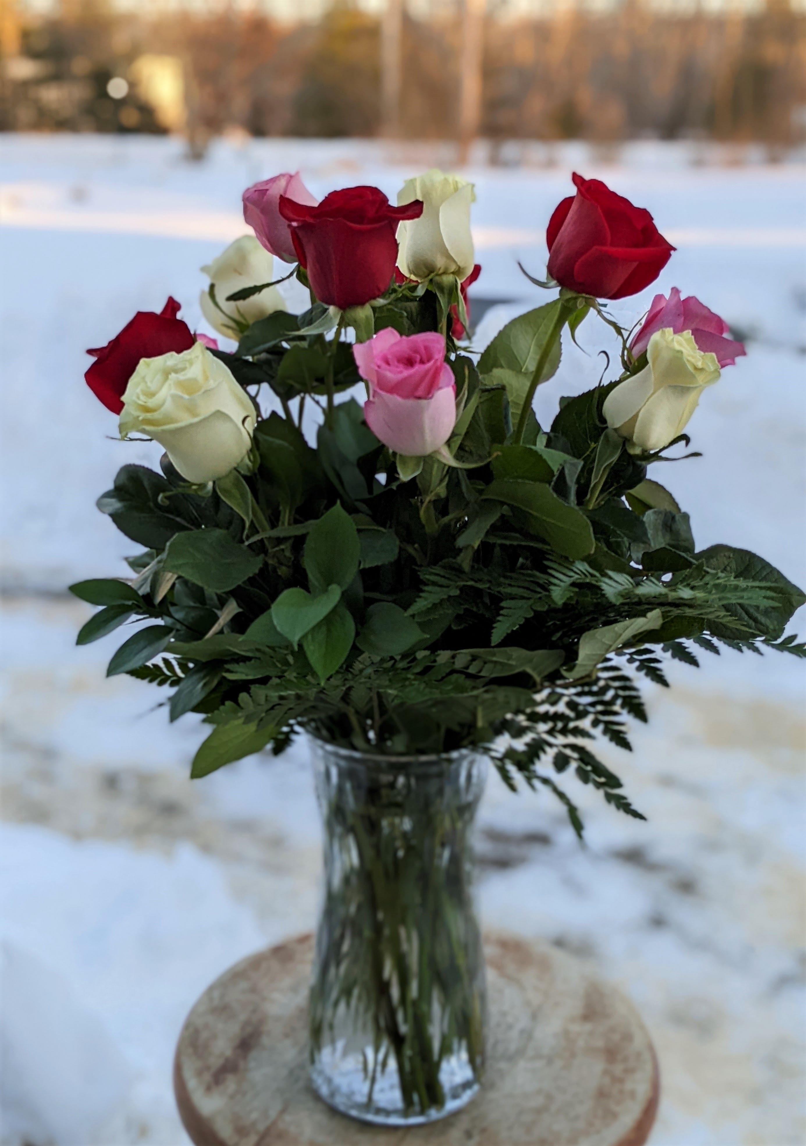 Bouquet of red, pink, and white roses in a clear glass vase