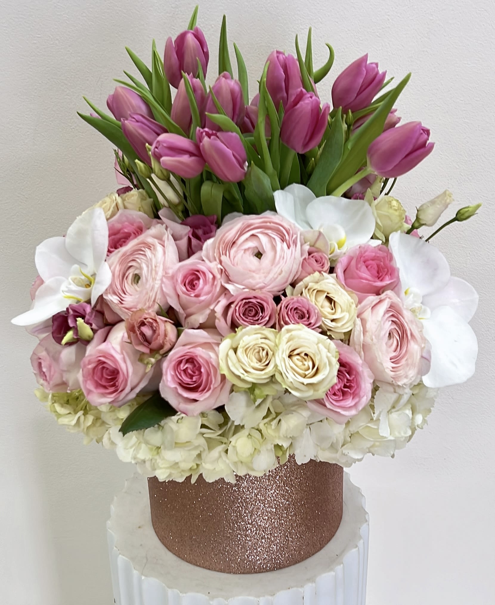 Pink tulips and roses arranged in a glittery rose-gold box