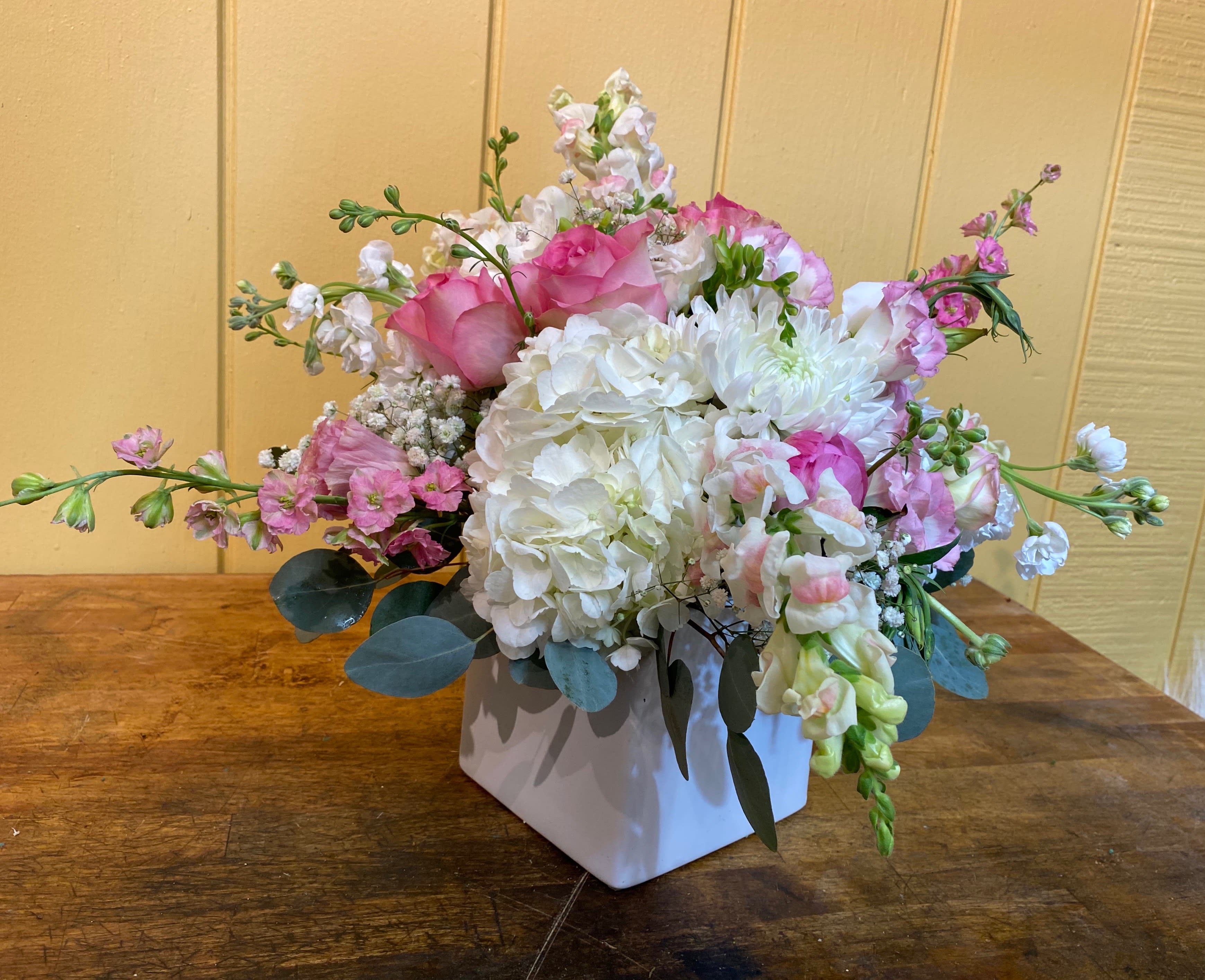 Pink and white floral arrangement in a white square vase