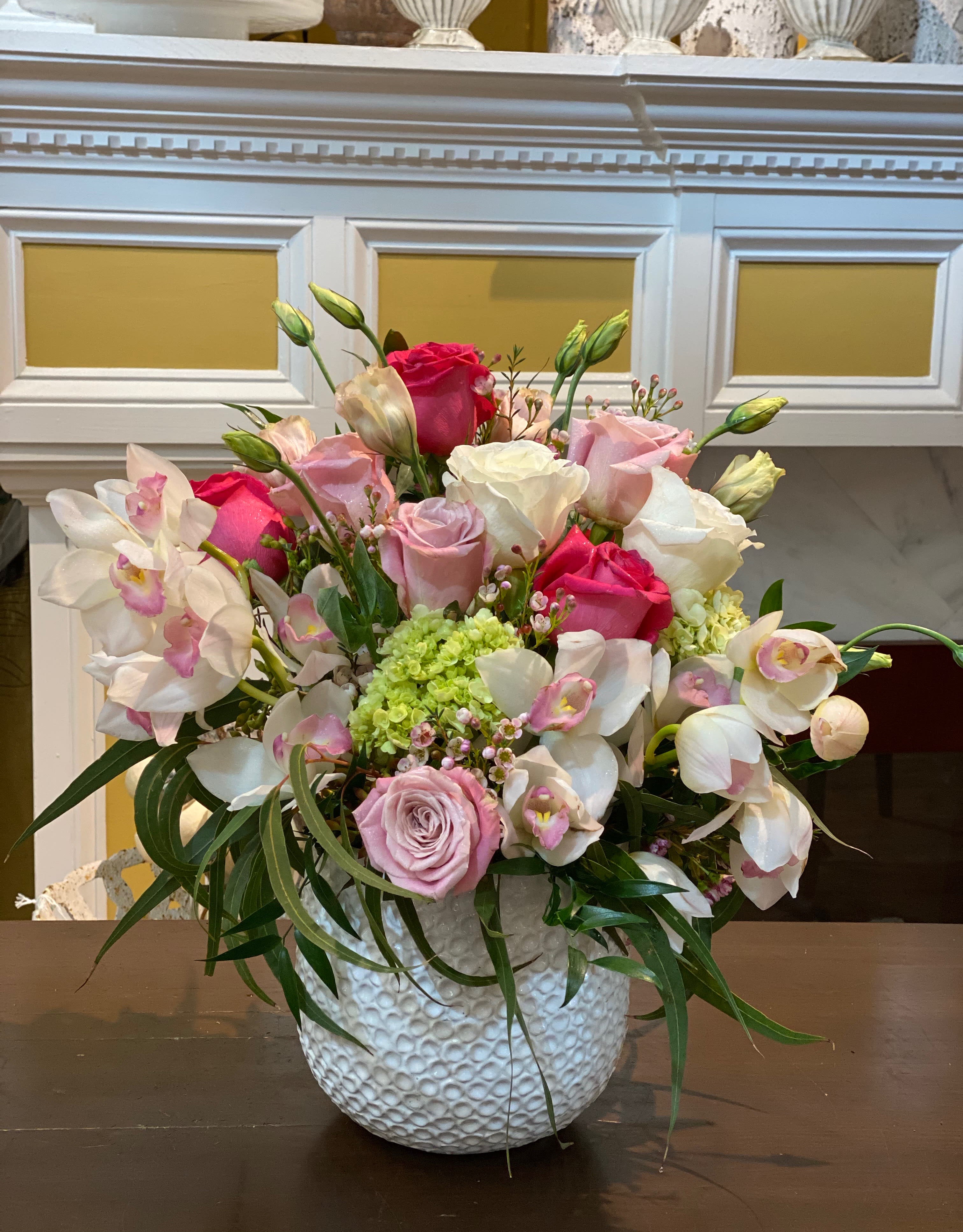Pink and white roses with orchids in a textured white vase