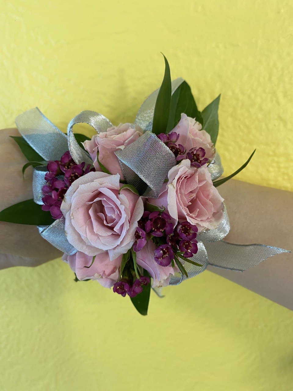 Pink rose wrist corsage with purple accent flowers and silver ribbon