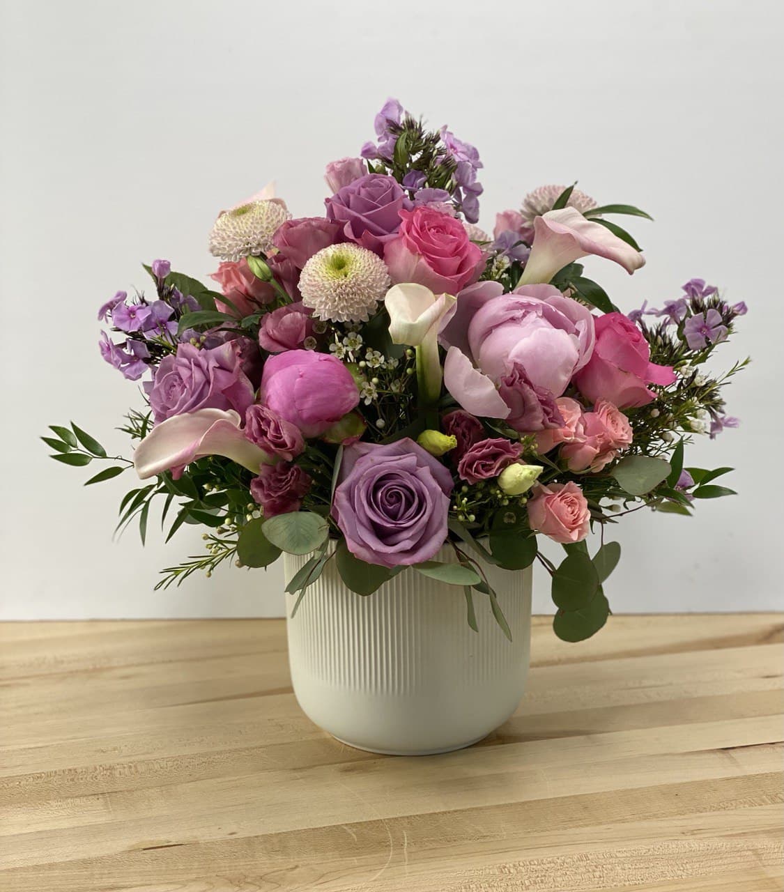 Mixed pink and purple flower arrangement in a white vase