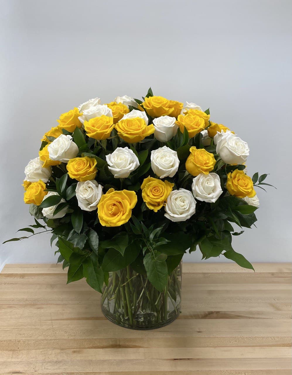 Bouquet of yellow and white roses in a clear glass vase