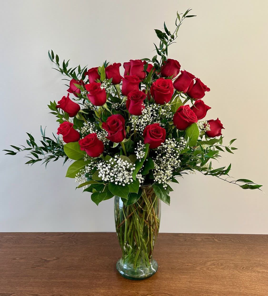 Red roses arranged in a clear glass vase with white filler flowers