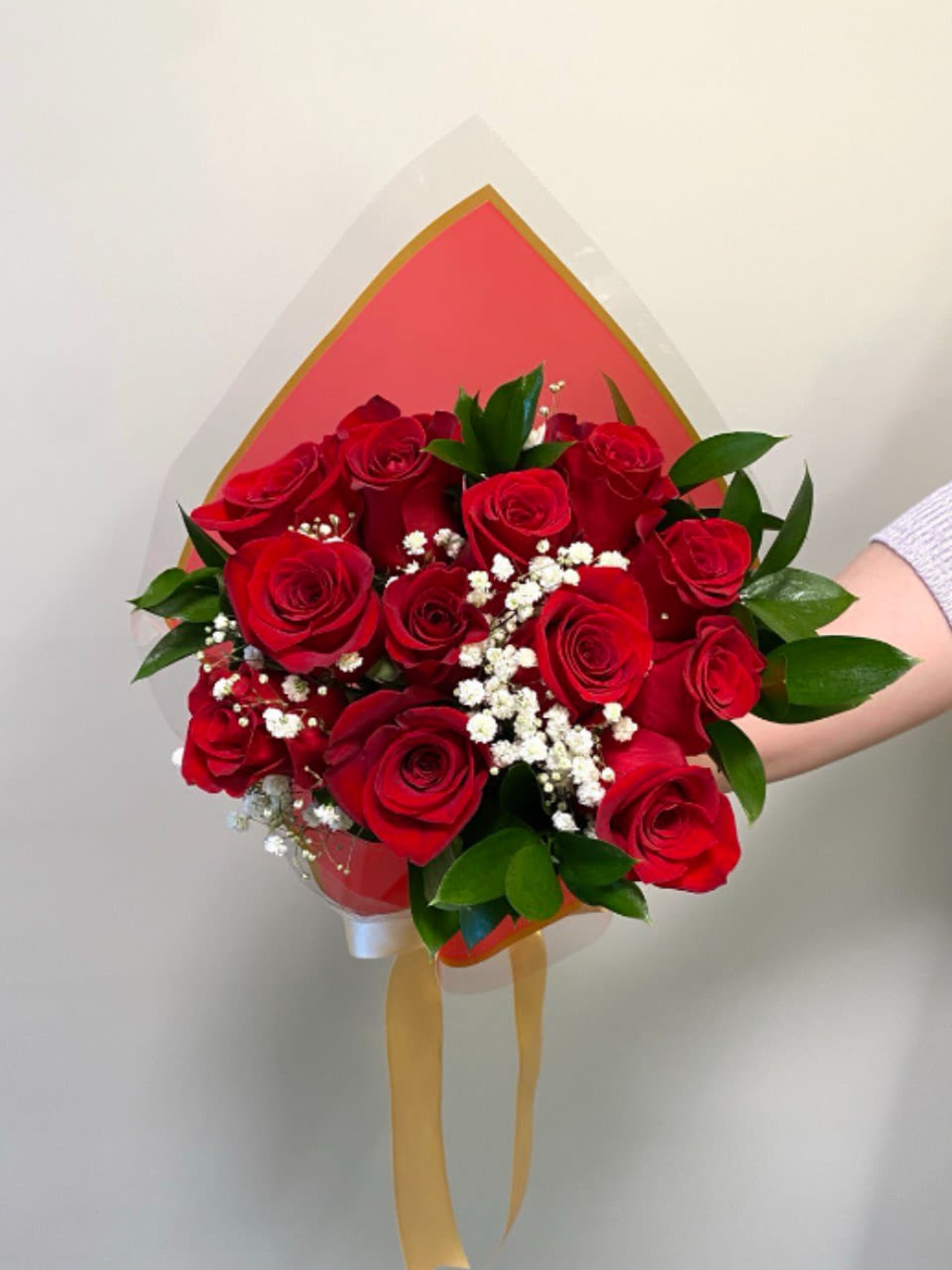 Bouquet of red roses with white baby's breath and green leaves in wrapping