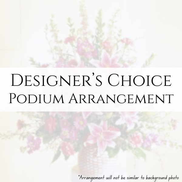 Designers Choice Podium Arrangement - Our Designer’s Choice Podium Arrangement is thoughtfully created by our designers in a mache container and styled to complement the setting and purpose of your event. Flowers, colors, and overall design are selected based on seasonal availability and our designers’ creativity to create a balanced and appropriate presentation piece.  If you have a preferred color palette, please include it in the special instructions, and we will do our best to accommodate. If you are able to share where the arrangement will be placed or how it will be used, that information is very helpful and allows our designers to tailor the style and scale of the arrangement accordingly.