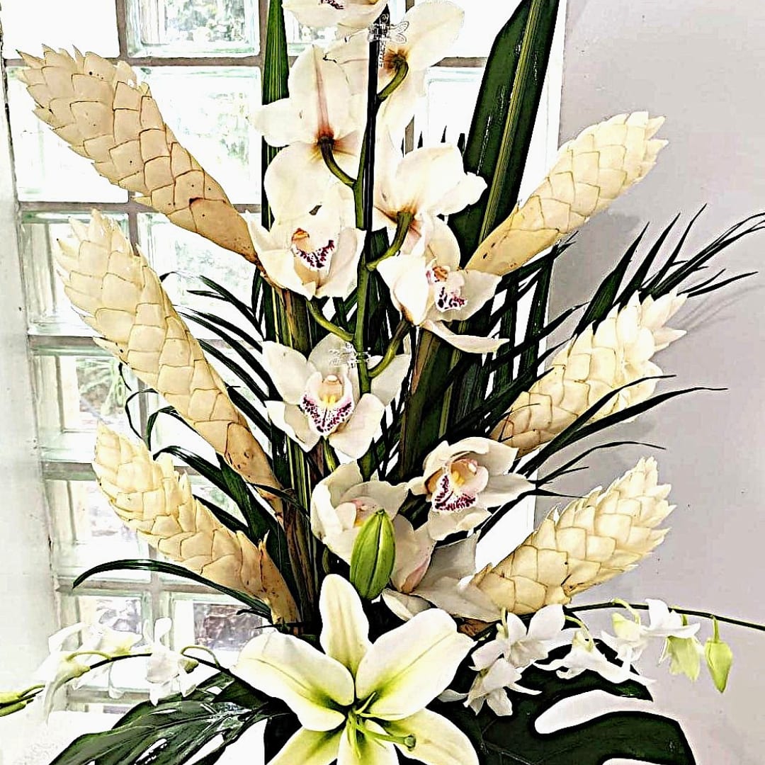 Tall arrangement of white orchids and lilies with pale cone accents