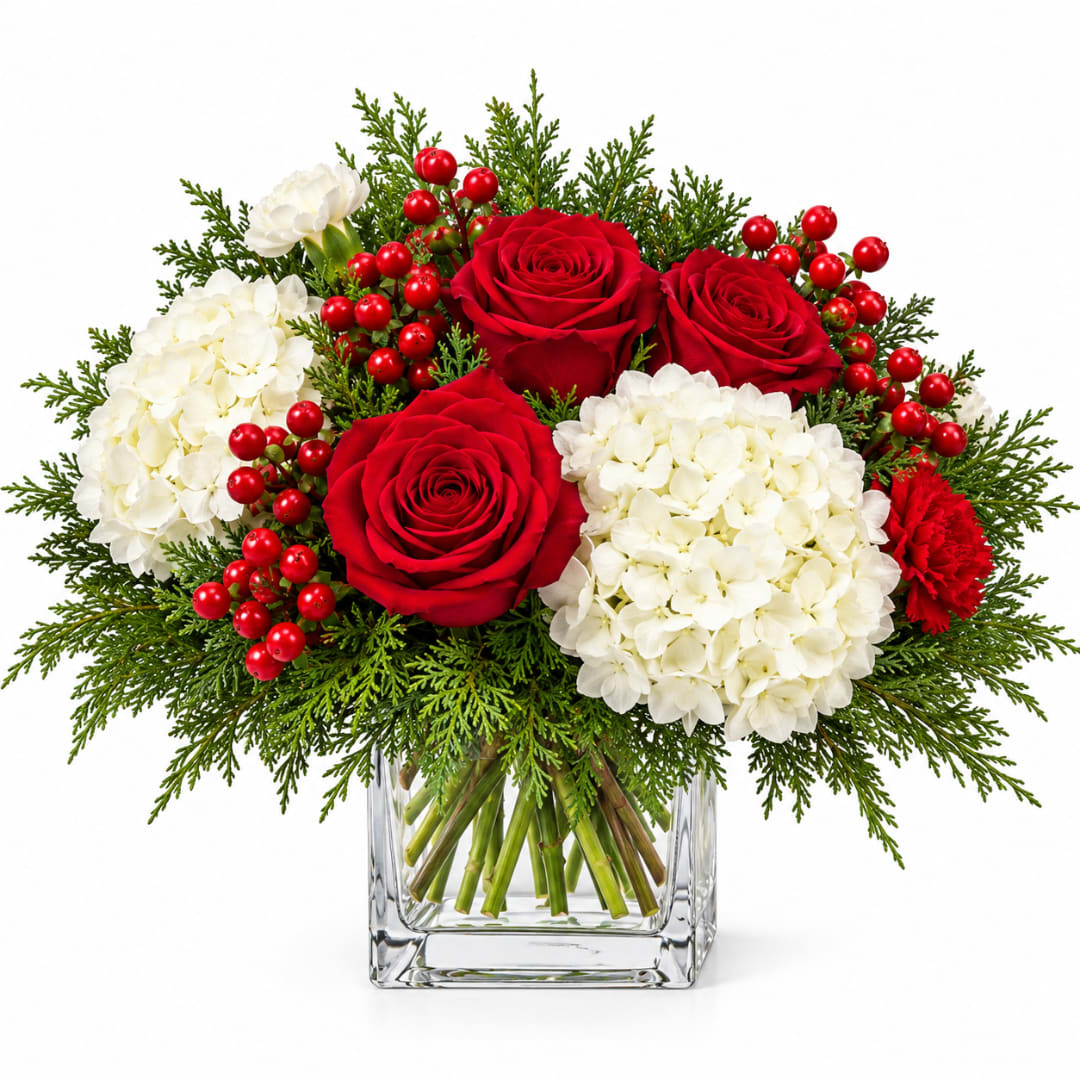 Red roses and white hydrangeas in a clear square vase with berries