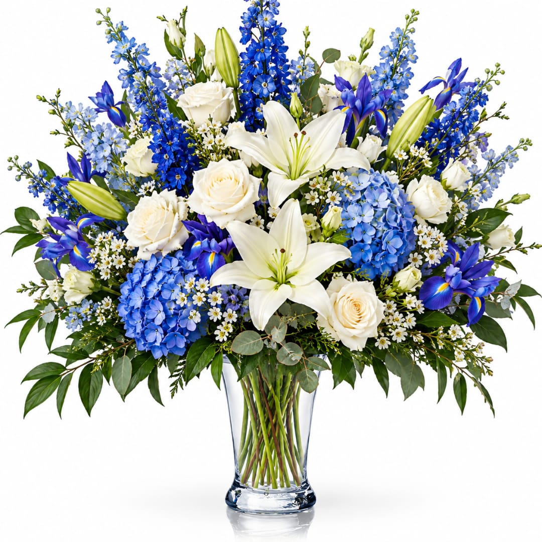 Blue and white bouquet with lilies, roses, and irises in a clear glass vase