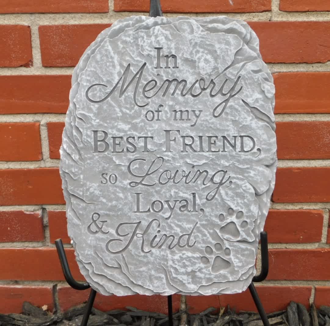 Gray memorial stone with engraved tribute text and paw prints