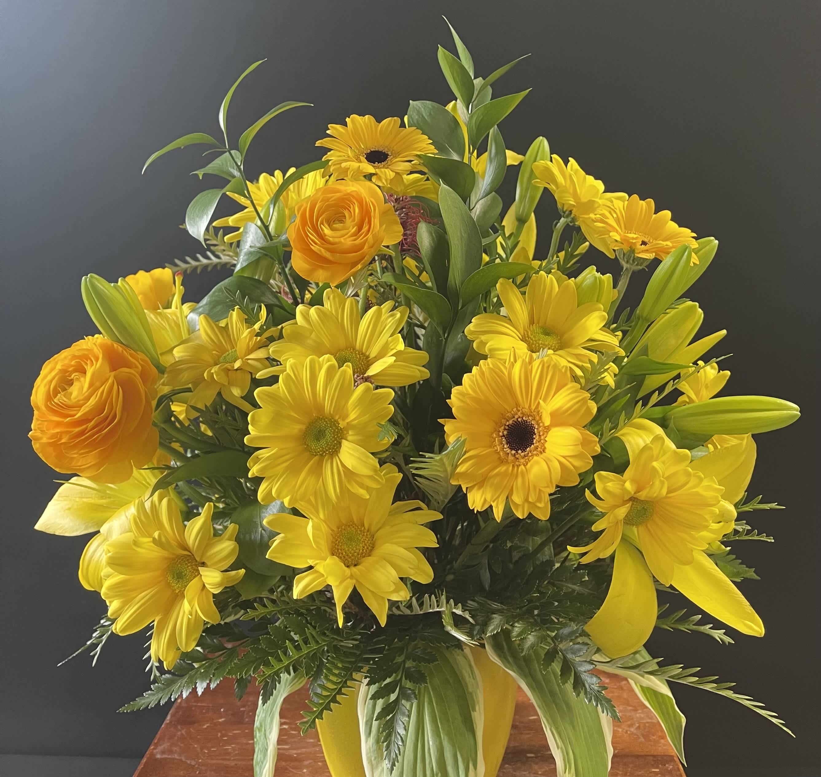 Yellow bouquet with daisies, lilies, and orange roses in a vase