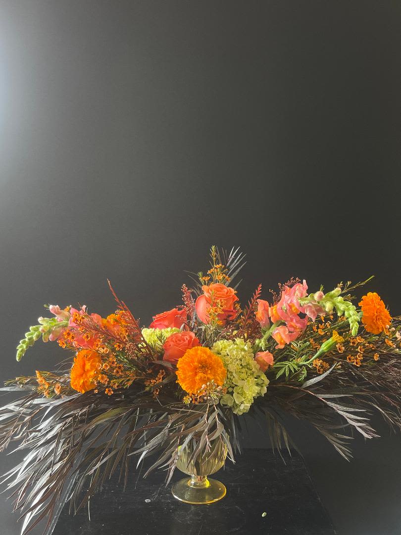 Orange and pink floral arrangement in a gold vase